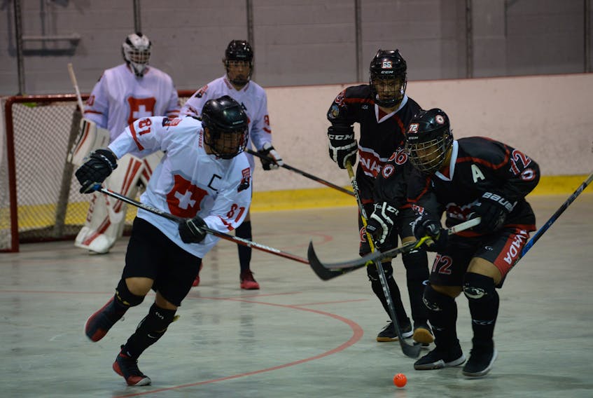 Swiss captain Raphael Enzler (81) and Team Canada assistant captain Avjot Sahota (72) battle for ball possession during the opening game of the men’s under-18 division of the 2018 world junior ball hockey championships Wednesday at the Mount Pearl Glacier. Watching the play are Canada’s Bryce Osepchuk (66) and goalie Romain Allemann and Yonas Berthoud (91) of Switzerland. The Canadian U18 team, whose roster includes four Newfoundlanders, won 6-2 and followed up with an 8-1 victory over Italy in an evening contest. — Joe Gibbons/The Telegram