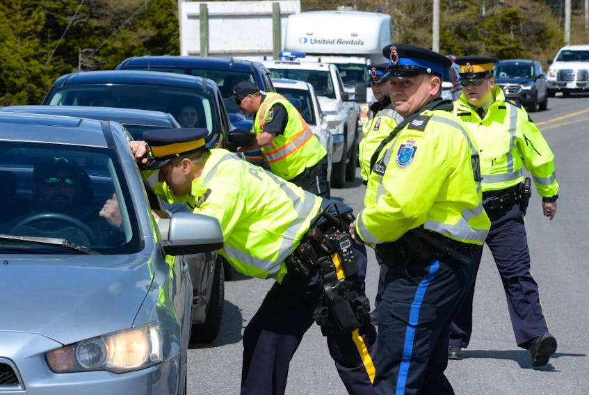 RCMP Const. Dave Bourden of the Holyrood RCMP speaks with a motorist at a checkpoint as RNC Sgt. Paul Didham of the RNC traffic services section looks up Salmonier Line on Friday during the beginning of Victoria Day long weekend roadside checks.