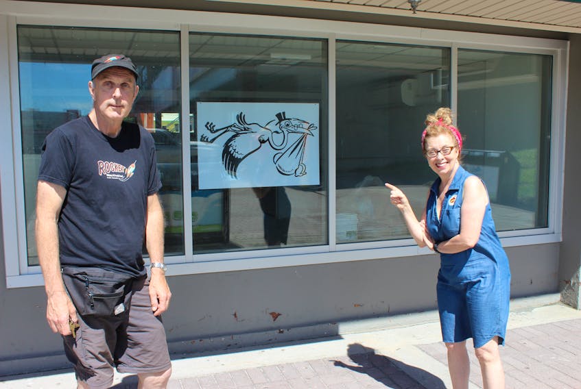 Dave Hopley and Kelly Mansell put a sign in the window of Rocket Bakery’s soon-to-be second location in Churchill Square.
