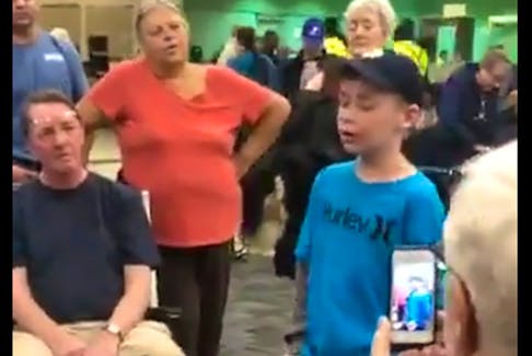 Still from Facebook video  — Young Liam Corrigan, backed by Sheldon Thornhill and Sean Sullivan (not shown), sings at Pearson International Airport while waiting for a flight in a video posted on Facebook by Michelle Sacrey Philpott.