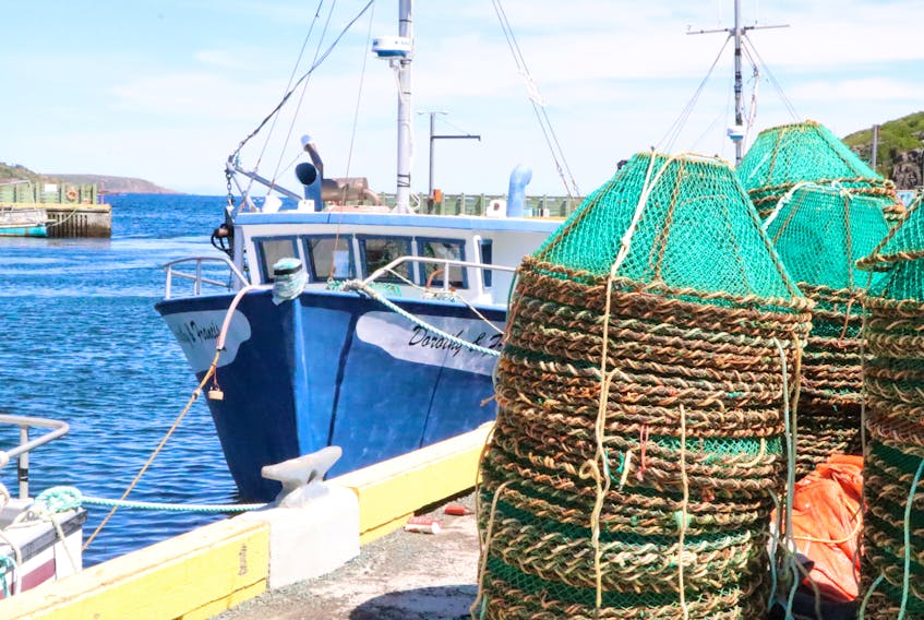Crab pots sit on the dock near a fishing boat in Petty Harbour in this Telegram file photo.