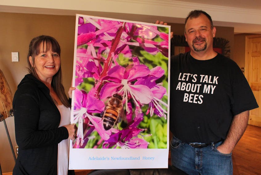 Brenda and Paul Dinn, who operate Adelaide’s Newfoundland Honey Inc. in Goulds, hold a sign they use to promote their products at the farmers’ markets they attend in the region. They will start a new venture this season with the opening of Adelaide’s Honey Bee, Pollinator and Wildflower Reserve.