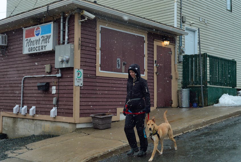 Jill Blackmore walks Charlie, one of many dogs she walks daily in her business Tails n’ Trails, passed the now closed Flower Hill Grocery in St. John's Tuesday.