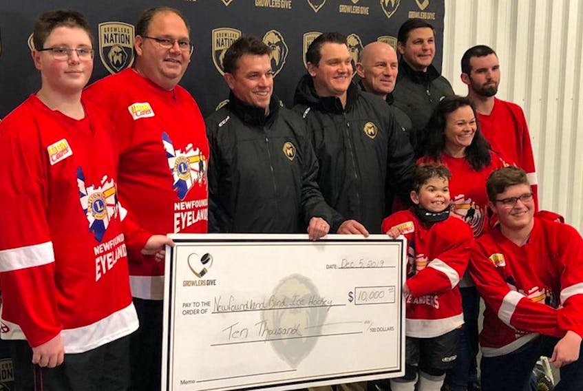 The Newfoundland Growlers made a $10,000 donation to the Newfoundland Blind Ice Hockey this past week. On hand for the presentation were (from left) top row: blind hockey player Brandon Joy, chief organizer Steve Joy, Growlers senior vice-president of hockey operations Trevor Murphy, Growlers head coach John Snowden, assistant coach Darryl Williams, assistant coach Adam Pardy and blind hockey player Dylan Bradbury. Accepting the cheque at the right is player Kaiden Benoit, accompanied by his mother Lisa Guest, and kneeling is player Zachary Harris. — Submitted