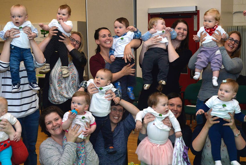 Some of the mothers and their babies who participated in this year’s Roots of Empathy program “raise” their babies in a salute to the program.