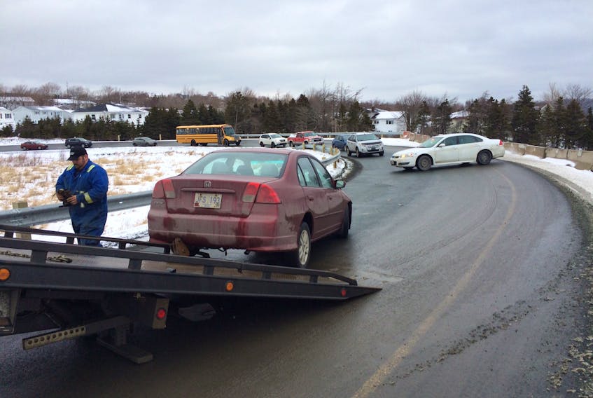 An employee of Avalon Towing prepares to haul a damaged Honda Civic onto his flatbed towing truck following a single vehicle accident on the Dunn's Road off-ramp to the new Team Gushue Highway (TGH) in Mount Pearl.