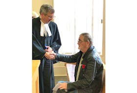 Thomas Snow (sitting) shakes the hand of his lawyer, Ken Hollett, after his court proceedings are adjourned in Newfoundland and Labrador Supreme Supreme Court Thursday morning. He’ll be back at the end of the month to be sentenced on a charge of conspiring to traffic oxycodone.