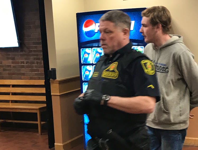 Lucas Dawe is escorted back to the holding cells after making a brief appearance in provincial court Wednesday morning. The 20-year-old is charged with interfering with human remains in Conception Bay South last weekend.