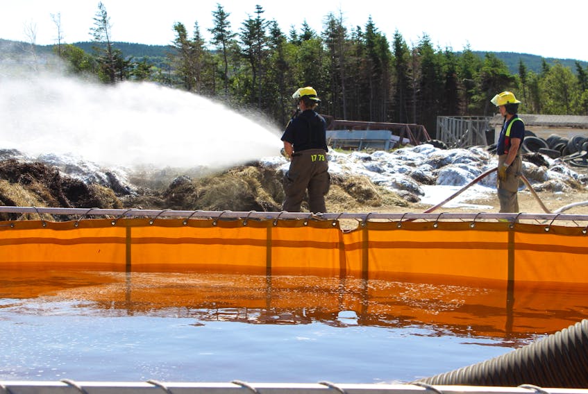 Firefighters from the St. John’s Regional Fire Department spray more than 50 bales of hay with a fire restricting foam to ensure flare ups don’t occur stemming from a stubborn fire at Lester’s Farm owned by Colin Lester on Brookfield Road on Wednesday morning.
