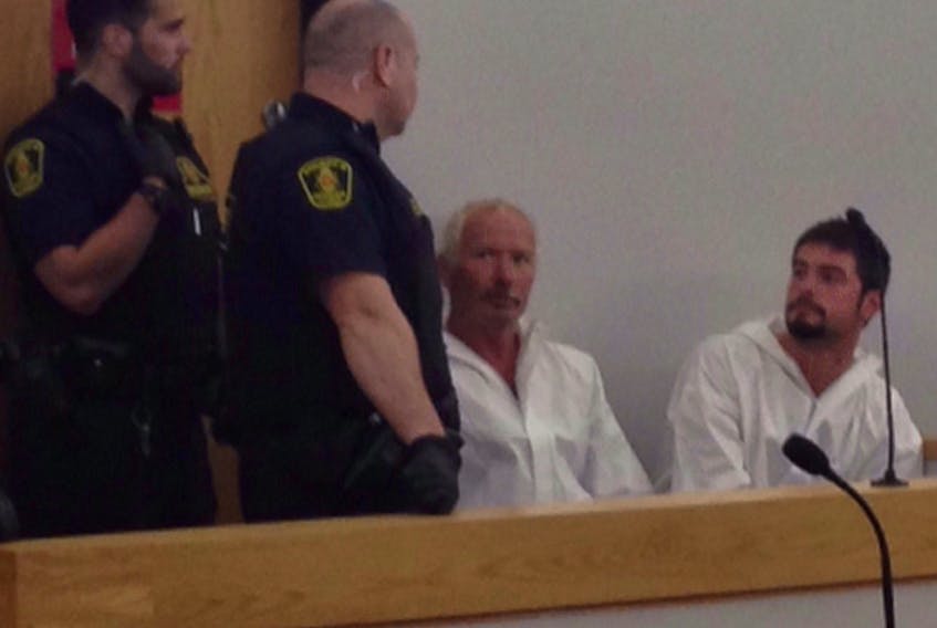 Wearing white Tyvek suits, father and son Stephen Alphonsus Maloney (second from right) and Mitchell Maloney sit upon entering courtroom No. 7 at provincial court in St. John's late Friday afternoon.