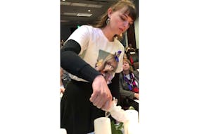 Memorial University engineering student Jenna Walsh lights a candle in remembrance of the 14 women who were shot and killed on Dec. 6, 1989 at Montreal’s École Polytechnique. Their names were read aloud at a vigil Thursday evening at Memorial University’s S.J. Carew Building. Twelve of the women killed were engineering students. Walsh wore a T-shirt bearing a picture of her cousin, Cortney Lake, who went missing in June 2017 and whose disappearance is classified as a homicide by the RNC. Lake’s body has not been found, and the only suspect in the case is her former boyfriend, Philip Smith, who killed himself in November 2017.