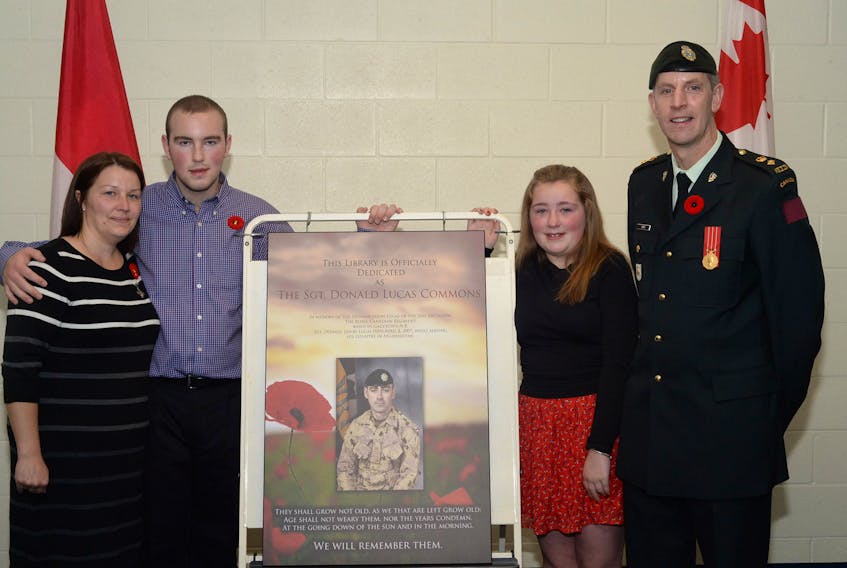 Natasha Lucas, son Matthew, daughter MacKenzie, and principal and reservist Kirk Smith display the plaque that will hang in the Octagon Pond Elementary School library in honour of the late Sgt. Donald Lucas