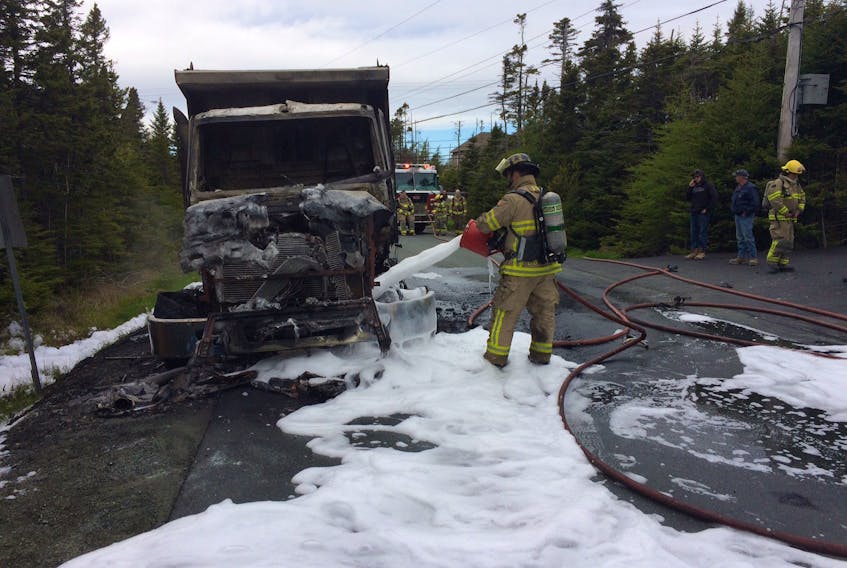 A firefighter sprays foam onto a burned-out dump truck in Portugal Cove on Thursday afternoon.