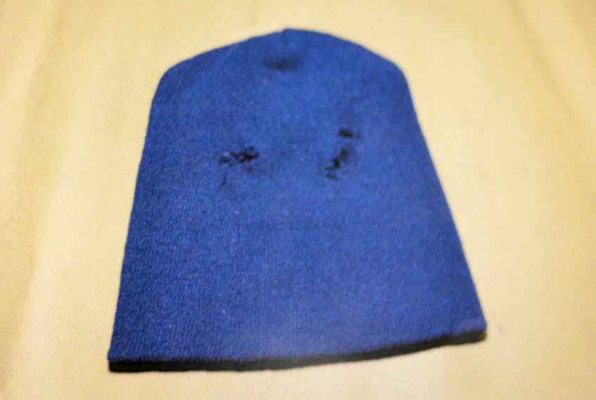 The mask in question: a navy toque with eye holes cut into it, found on the sidewalk on Forest Avenue behind the Captain’s Quarters hotel, the morning after Larry Wellman was shot and killed.
