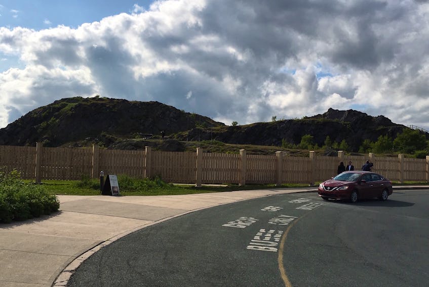 A car slows down near the fence erected on Signal Hill this week, as Rick Mercer does an interview with CBC in front of it, July 17. —