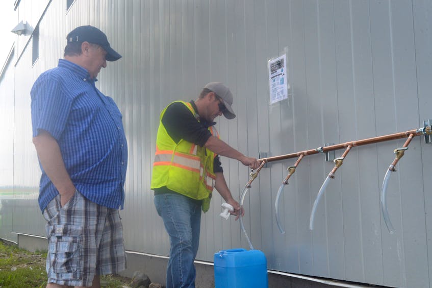 Cowan Heights resident Roger Hollahan (left) gets a five-gallon container of water filled by a City of St. John’s waterworks department employee — who didn’t want to give his name — at the Blackler Avenue depot on Wednesday afternoon.