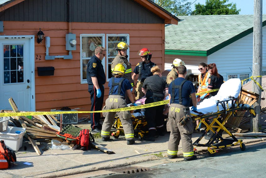 Eastern Health paramedics and St. John’s Regional Fire Department firefighters tend to two women on the patio of a house on Goodridge Street in St. John’s Tuesday after a runaway car crashed onto the patio.