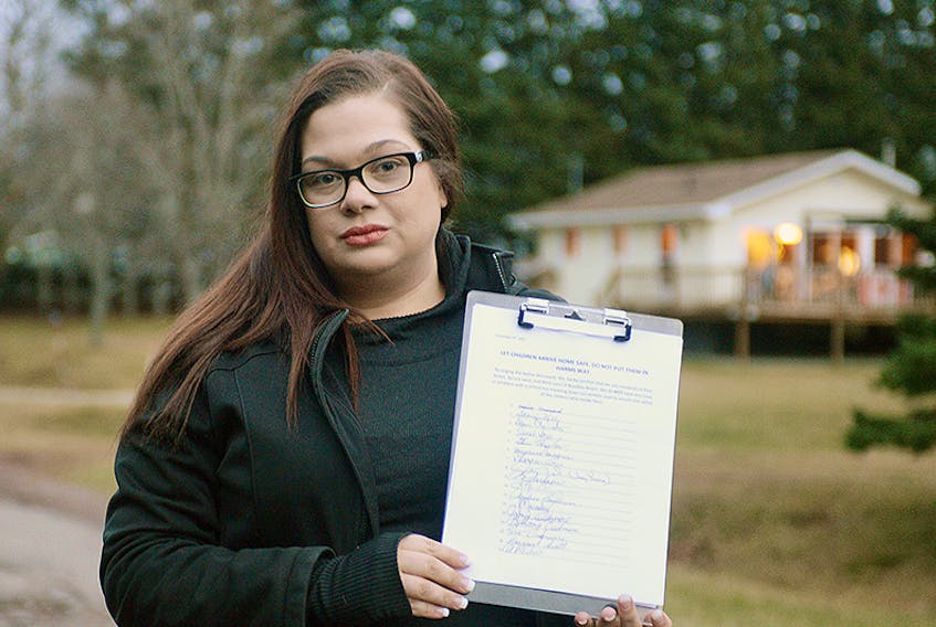 Parent Kerri Kelly holds a petition with the signatures of residents who live on and near the private road, Pine Street, in Brackley Beach, stating they do not have an issue with a school bus going down the road. Currently, the bus stop is located before the road and right next to a convicted sex offender’s home.  ©THE GUARDIAN