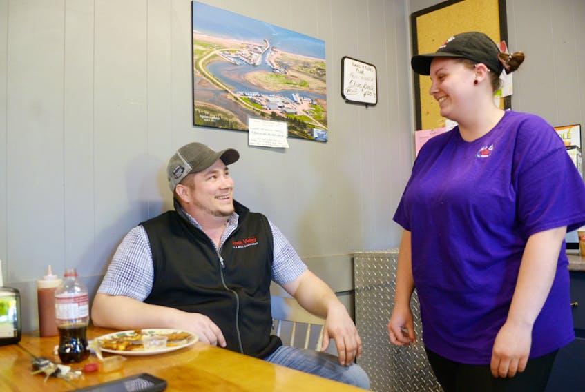 Tignish residents Sean McGivern, left, and April McInnis chat inside Shirley’s Café with an overhead picture of the town behind them. Both were surprised to hear of Tignish residents being turned away by a Charlottetown hotel on New Year’s Eve because of where they were from.