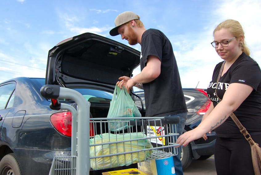 Elijah Henderson and Kyla MacKenzie unload plastic bags full of groceries at the Atlantic Superstore Thursday. A bill to ban plastic shopping bags is working its way through the legislature and is ready for the third and final reading.