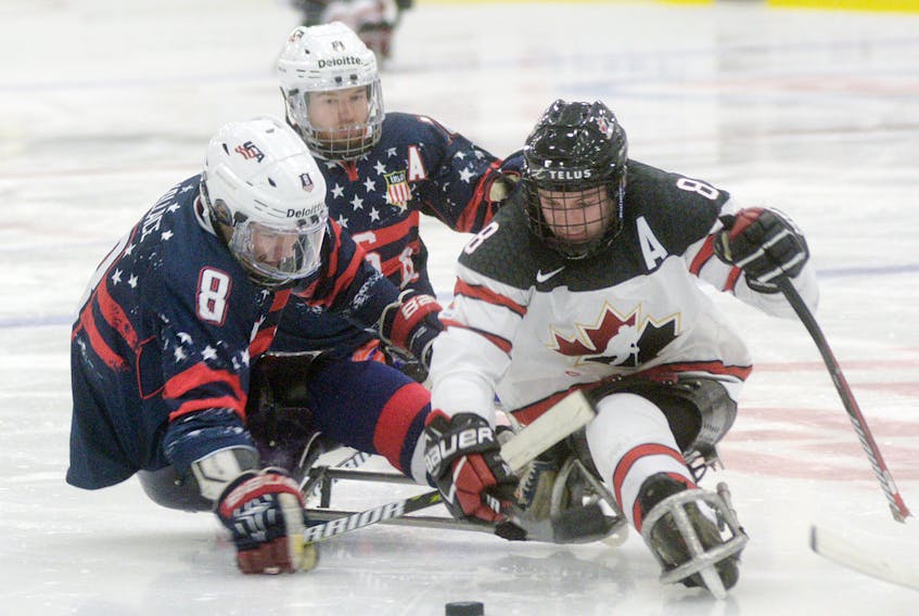 Team Canada forward Tyler McGregor moves the puck away from Team USA players, from left, Jack Wallace and Declan Farmer during the Gold Cup Game of the 2017 World Sledge Hockey Challenge at MacLauchlan Arena.
