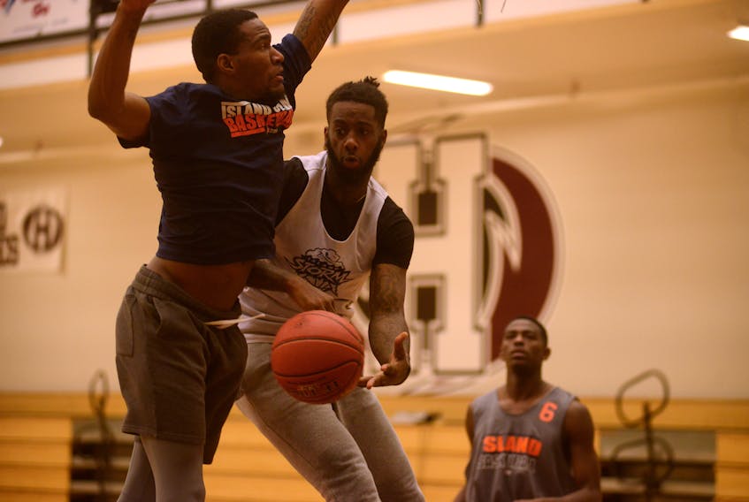 Torrence Dyck Jr., centre, dishes to a cutting teammate as Du’Vaughn Maxwell defends during Thursday’s Island Storm practice at Holland College.