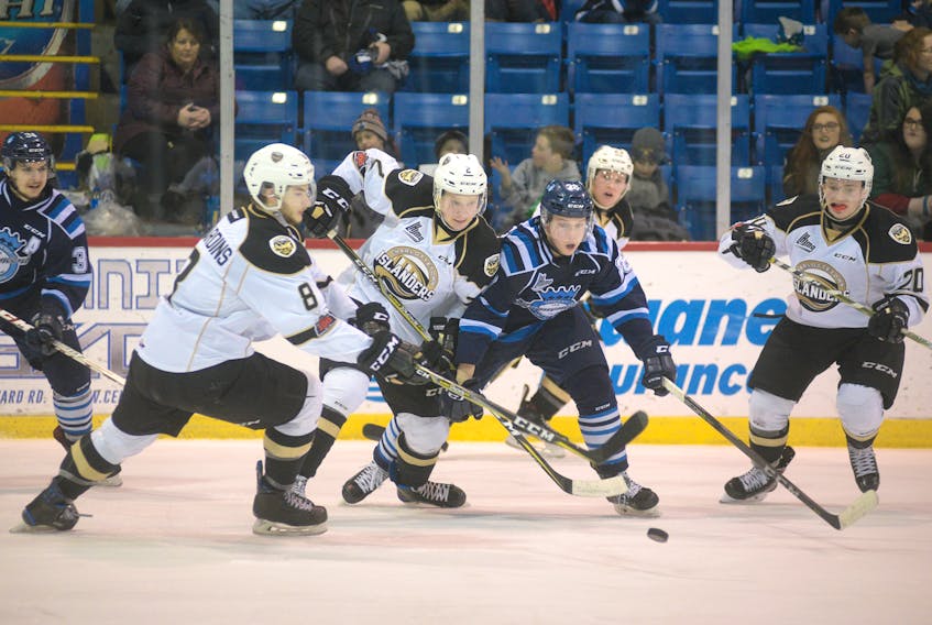 Chicoutimi Sagueneens' Vincent Milot-Ouellet battles for control of the puck against Charlottetown Islanders defensemen Taylor Egan and Olivier Desjardins during third period action Saturday at the Eastlink Centre.
