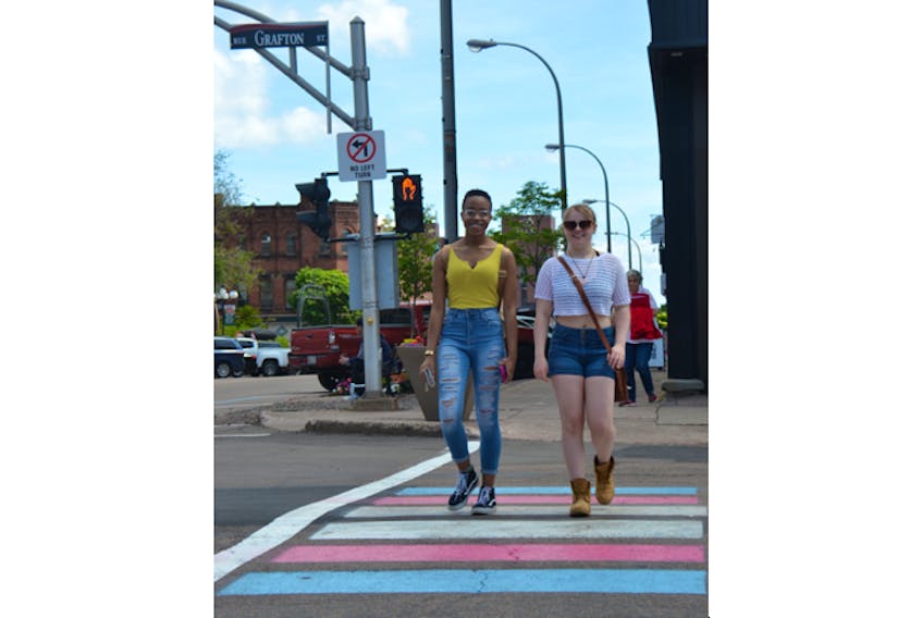 Josie Hood, right, and Sara Rixon cross the intersection at Grafton and Queen streets in downtown Charlottetown on July 11. The crosswalks were recently repainted in advance of Charlottetown’s Pride parade, showing the colours of the pride flag and the trans flag.