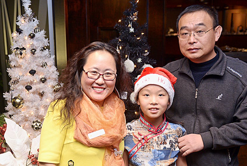 Amy Tian, left, celebrates with her daughter Jamie and husband Flaming Jia during the P.E.I. Association for Newcomers to Canada’s Christmas Open House at the Confederation Centre of the Arts Tuesday night. Amy and Jamie, who moved to P.E.I. in 2014, said this Christmas will hold some extra meaning for the family with Jia now living in the province. The mother and daughter spent the last three Christmases by themselves in P.E.I. while Jia was in China.  ©THE GUARDIAN