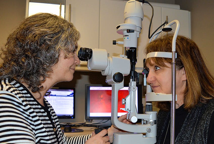 Catherine Arsenault, left, an optician with Family Vision Centre in Charlottetown, tests out a piece of equipment with fellow optician Paula McKenna. The P.E.I. Association of Optometrists has begun an information campaign to clear up some confusion about what the province does and does not cover.  ©THE GUARDIAN