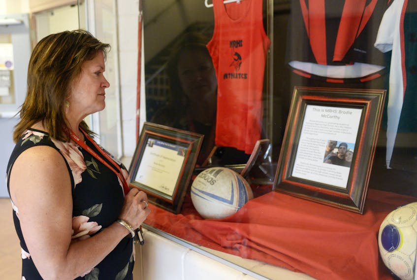 Principal Seana Evans-Renaud looks over a tribute to student athlete Brodie McCarthy, who died on Sunday after being injured during a rugby game on Friday. Evans-Renaud described McCarthy as a sports fanatic who was well-liked by both his peers and teachers.