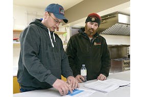 Fishermen Robbie Moore, left, and Dave MacEwen look over documents regarding the North Shore Community Council's upcoming Covehead Bay review. Both said the review is a waste of taxpayer money, as well as an attack on their industry.  ©THE GUARDIAN