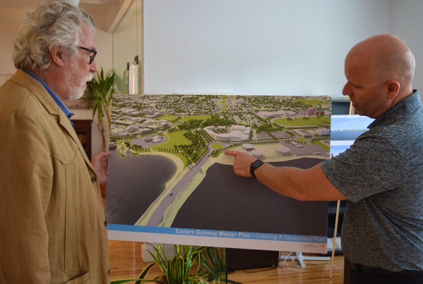 George Dark, left, an urban planner from Toronto, and Coun. Greg Rivard, chairman of Charlottetown’s planning committee, go over one of the drawings from the Eastern Gateway Waterfront Master Plan. This artistic concept depicts Charlottetown as approached from the Hillsborough Bridge, with a roundabout at Grafton/Water/Riverside streets and a new beach on the left.