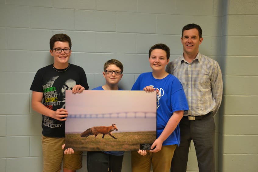 Norbert Carpenter, right, principal at Montague Consolidated School, joins Grade 7 students from Montague Intermediate School Keaton MacDonald, left, Alex Beck and Isaiah Williams at the intermediate school on June 19, as they pose with a photograph given to them by the province as an acknowledgment of the work they did to get the red fox named as P.E.I.’s provincial animal.