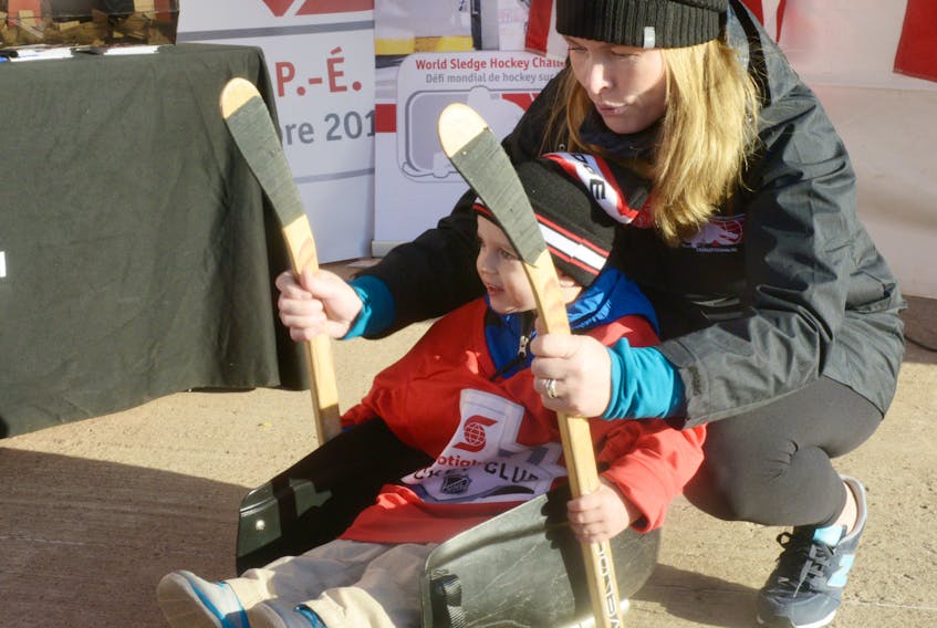 Three-year-old Cameron Smith, of Stratford, gets a sledge hockey demo from Meredith Caissie during the Rogers Hometown Hockey event in Charlottetown. Caissie is a member of the organizing committee for the 2017 World Sledge Hockey Challenge.