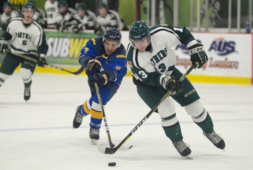 Moncton forward Marc-Anthony Therrien, left, tries to lift the stick of UPEI Panthers forward Beau McCue during Wednesday Atlantic University Sport men’s hockey game in Charlottetown.  Jason Malloy/The Guardian