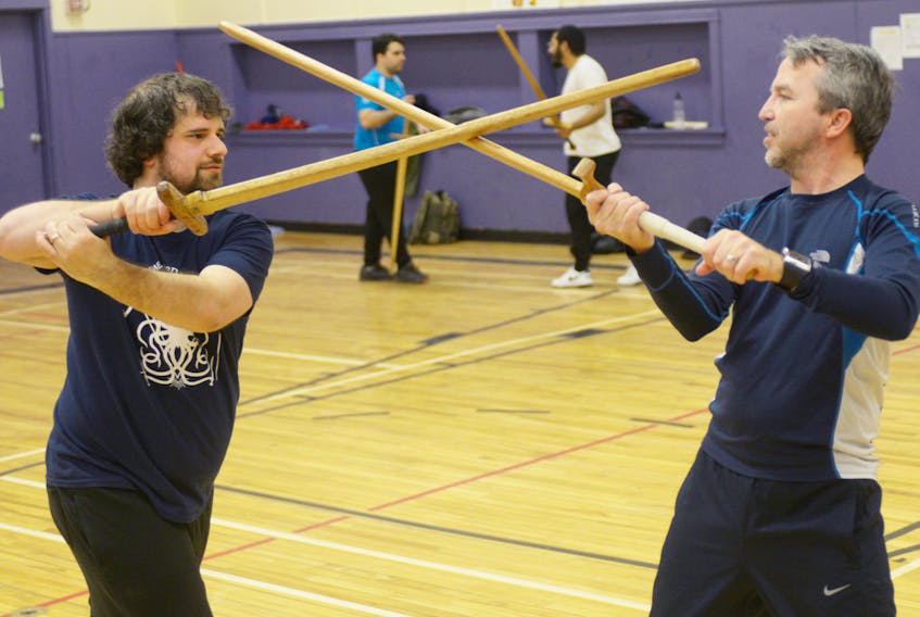 Evan Hill, left, and Michael Smallwood, right, battle with some wooden long swords during a Maritime Sword School practice at St. Jean Elementary School in Charlottetown on Jan. 21, 2018.