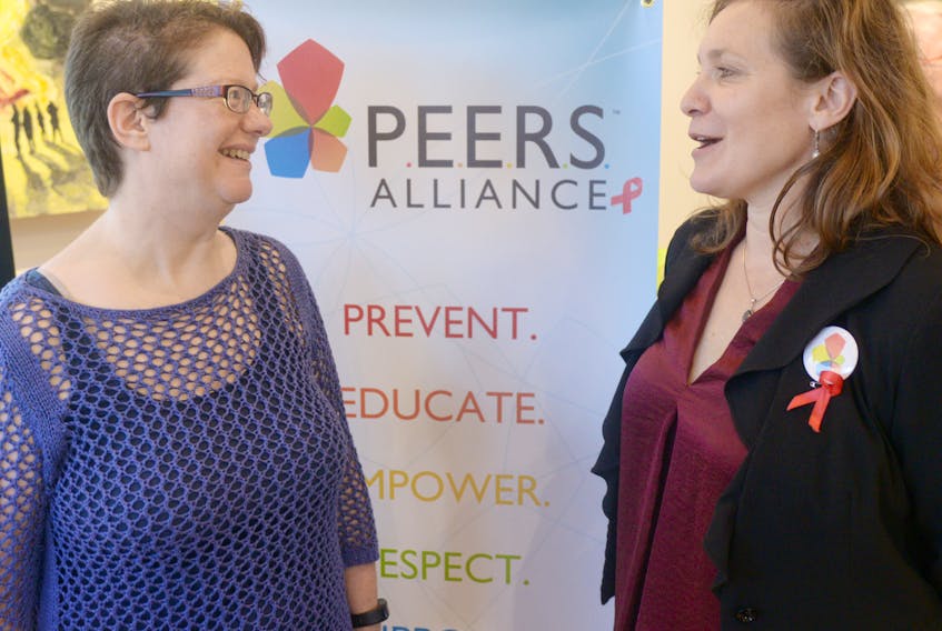 Board chair Nola Etkin, left, and executive director Cybelle Rieber stand next to the new logo for PEERS Alliance, which is the newly re-branded name for AIDS P.E.I., during an unveiling ceremony held at The Guild on Tuesday. (MITCH MACDONALD/THE GUARDIAN)