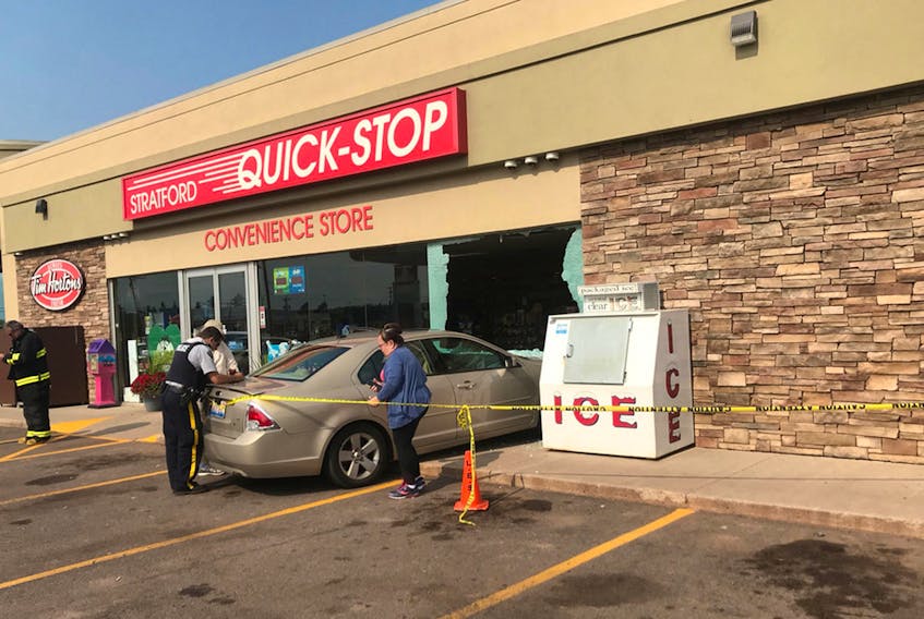 A police officer takes information after a sedan drove into the front of the Stratford Petro-Canada on Saturday.