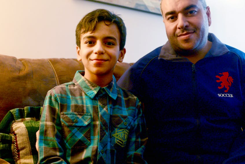 Twelve-year-old Basel Al Rashdan, left, and his father Amjad sit together in their Charlottetown home nearly two years after arriving in P.E.I. as Syrian refugees. (Mitch MacDonald/The Guardian)