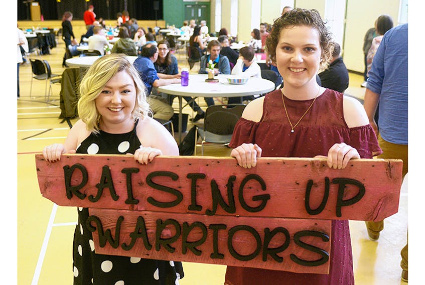 Jenny Cooper, left, and Breanna Ching hold the sign for their Raising Up Warriors mental health fundraiser, which brought in more than $2,400 at Murphy’s Community Centre on Saturday. The two said they hope to host the event, which focused on recovery and hope, again after exceeding their original fundraising goal of $2,100.  ©THE GUARDIAN