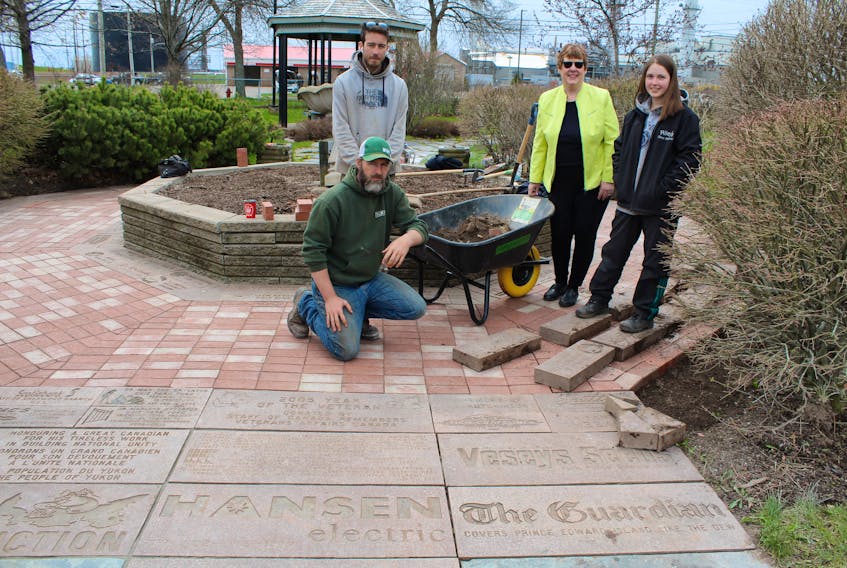 Employees from Island Grown Sod restored the memorial bricks at the Joseph A. Ghiz Memorial Park in Charlottetown last month. Landscapers Adam Chaloner and Riley McInnis, project co-ordinator Marlene Bryenton, and landscaper Riley Chappel stand near one of the wheelbarrows of weeds removed from around the bricks last month.