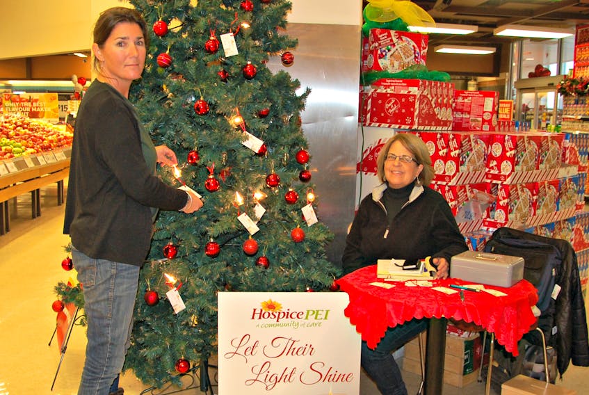 Liz Parsons turns on a light in memory of her special friend at the “Let their Light Shine” Hospice P.E.I. tree. Lorna Jenkins, a Hospice volunteer, knows what Parsons is going through because she has also dealt with death in her family and helps other families as a volunteer with hospice.