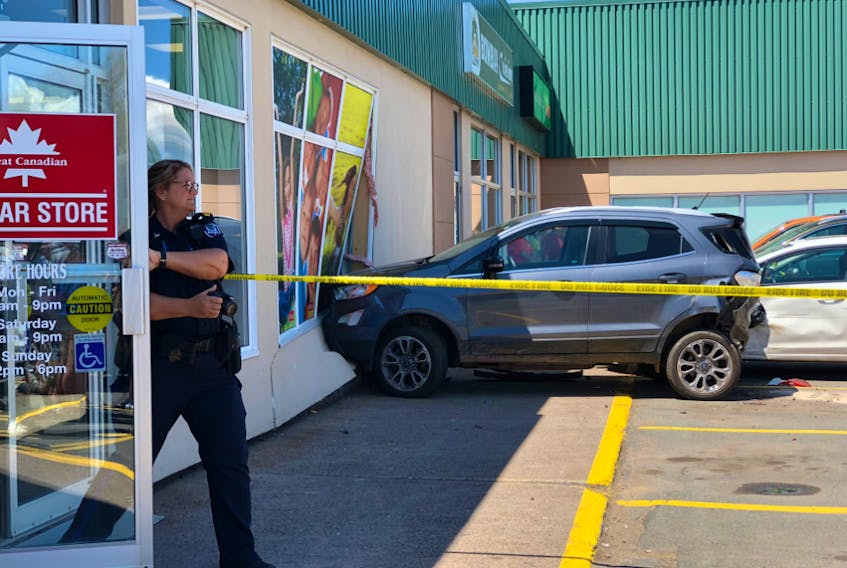 A Charlottetown police officer is seen leaving The Great Canadian Dollar Store on June 4 during an investigation into a crash that caused extensive damage to the store and to several parked vehicles in the area. Photo by Beth Johnston