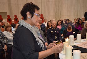 Mary Moore-Phillips, a band council member of the Lennox Island First Nation, lights a candle in memory of the 14 women murdered in the Montreal massacre of 1989 and the 10 Island women who have been murdered since that year. A memorial service was held in Charlottetown on Thursday.