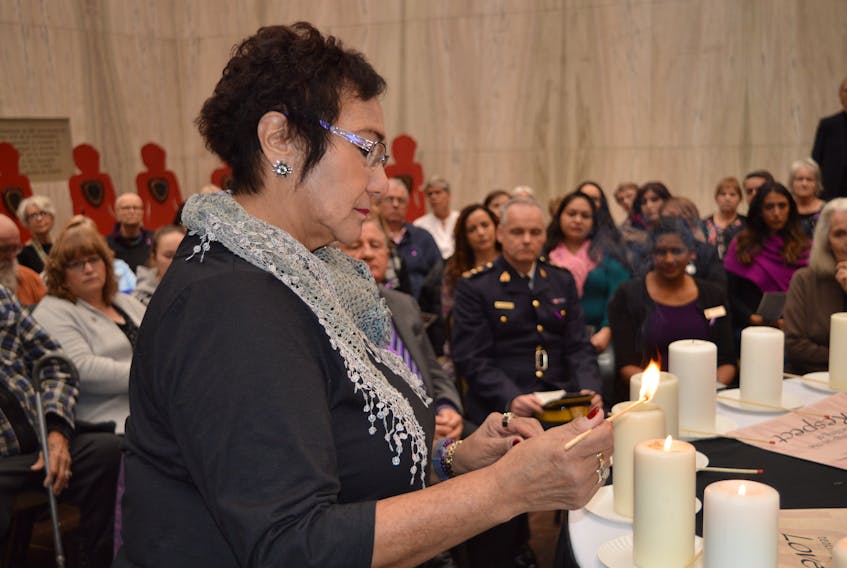 Mary Moore-Phillips, a band council member of the Lennox Island First Nation, lights a candle in memory of the 14 women murdered in the Montreal massacre of 1989 and the 10 Island women who have been murdered since that year. A memorial service was held in Charlottetown on Thursday.