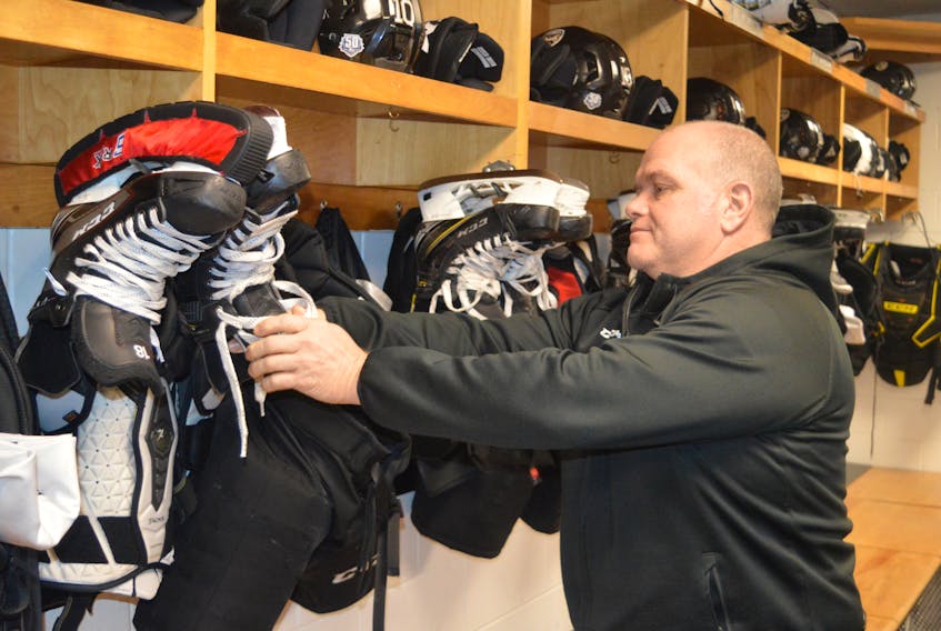 Charlottetown Islanders assistant coach Guy Girouard adjusts a pair of skates in the team’s dressing room at Eastlink Centre on Monday. The existence of the major junior hockey team and the pro basketball Island Storm makes a new arena project ineligible for federal government funding.