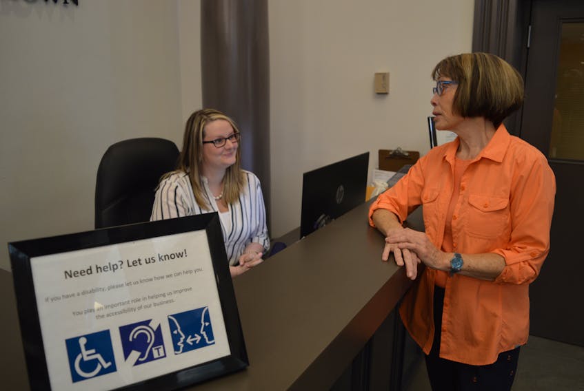 Rachel McPhee, left, receptionist at City Hall in Charlottetown, talks to Brenda Porter, a member of the city’s board of persons with disabilities, about the new looping technology installed in the building.