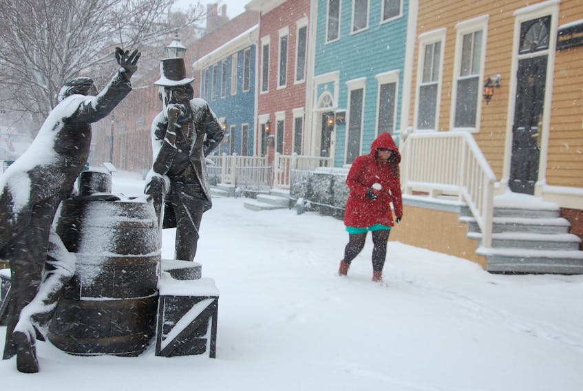 Joyce Moase walks along Great George Street Thursday in blowing snow past the bronze statue of two Fathers of Confederation both named John Hamilton Gray.