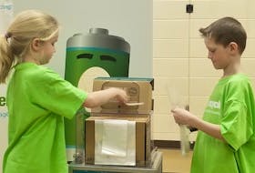 Rachel Frizzell and Cooper Fairhurst, students at Central Queens Elementary in Hunter River, demonstrate how to properly dispose of batteries.